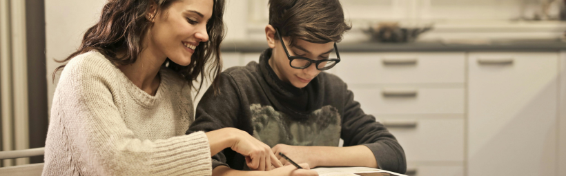 An adult and a child reading at a kitchen table.