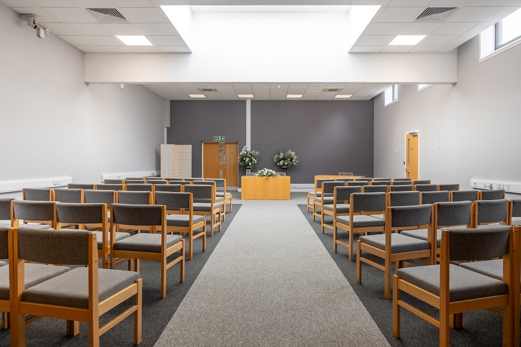 The Ampthill Room in the Court House, Ampthill. The photo shows two rows of guest chairs either side of the room, with the signing table at the far end, in the middle. The room is decorated in various shades of grey and white.