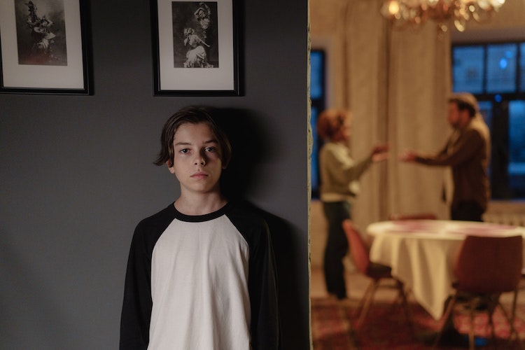 Child, hiding around a corner, listening to their parents arguing