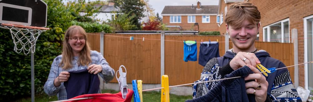 Foster teen and carer hanging washing